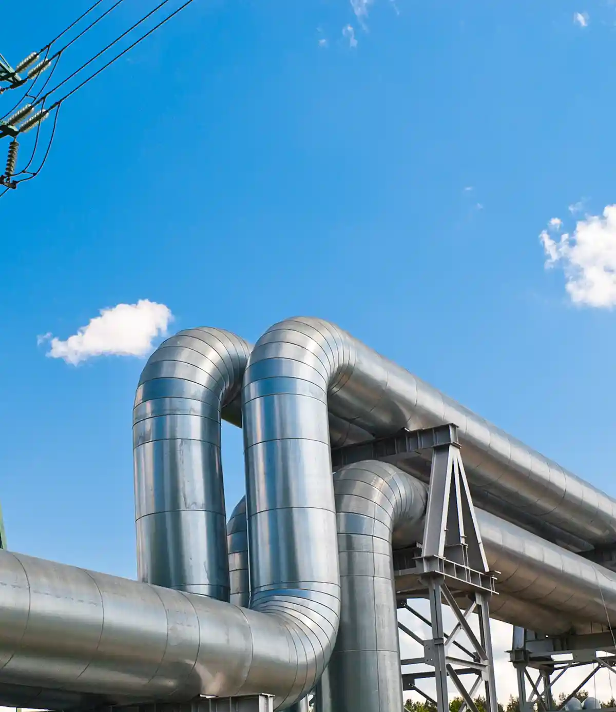 Pipeline und Stromleitung gegen blauen Himmel mit Wolken